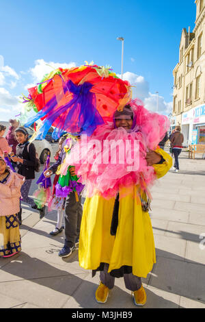 Hastings, East Sussex, UK. 11. Feb 2018. Eine bunte Teilnehmer, auf eine brillante sonniger Tag, für die Parade der eingerichteten Sonnenschirme am 5 tag Fett Dienstag / Mardi Gras Karneval. Stockfoto