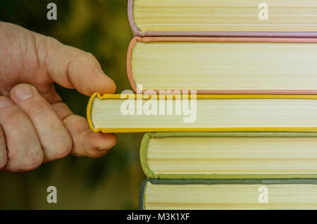 Die Hand eines Mannes zieht ein Buch aus der shelfю Close-up. Bildung Konzept Stockfoto