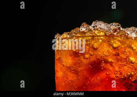 Soft Drink mit crushed Ice Eiswürfel im Glas auf dunklem Hintergrund mit Kopie Raum isoliert. Es ist ein Tropfen Wasser auf die gläserne Oberfläche. Stockfoto