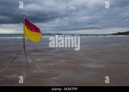 Rote und gelbe Flagge am Strand, die darauf hinweist, dass der Strand von Rettungsschwimmern bewacht wird. Bigbury Strand, Devon, Großbritannien. Stockfoto