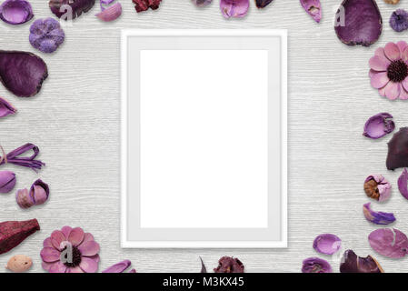 Bilderrahmen mit isolierten weißen Raum für das Bild oder Text. Blumenschmuck um den Rahmen. Weiß Schreibtisch aus Holz im Hintergrund. Ansicht von oben. Stockfoto