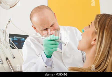 Reife männliche Zahnarzt über zahnmedizinische Bohrgerät auf weibliche Patienten - Karies Behandlung Stockfoto