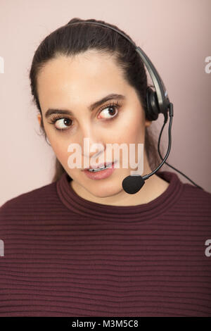Nahaufnahme Porträt einer jungen Frau hören mit Aufmerksamkeit, während die mit modernen Headset während der Arbeit als virtueller Assistent Stockfoto