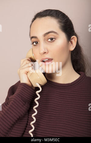 Junge Frau im Gespräch über das Festnetz Telefon mit Schnur sprechen mit Ihrem Mund in Nahaufnahme 7/8-Ansicht öffnen Stockfoto