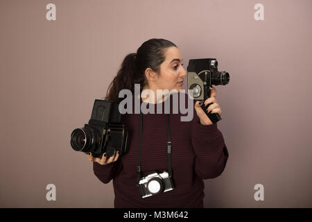 Junge Frau mit zwei klassische Kameras, eine für Standbilder, eine für Video, mit einem kleinen, kompakten Hängen um den Hals in einem Konzept der Fotografie als Stockfoto