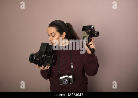 Junge Frau mit zwei klassische Kameras, eine für Standbilder, eine für Video, mit einem kleinen, kompakten Hängen um den Hals in einem Konzept der Fotografie als Stockfoto