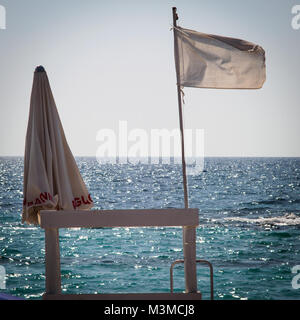 Gallipoli (Italien), August 2017. Weiß wehende Flagge auf einem Rettungsschwimmer Stuhl am Strand von Padula Bianca. Quadratischen Format. Stockfoto