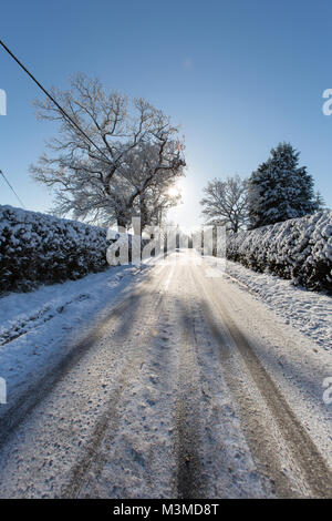 Dorf von Coddington, England. Silhouetted winter Blick eines ländlichen nicht knirschte Straße, in ländlichen Cheshire. Stockfoto