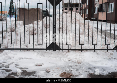 Metall schwarz Zaun. Im Winter Schneeverwehungen auf dem Parkplatz. In der Nähe von zu Hause. Stockfoto