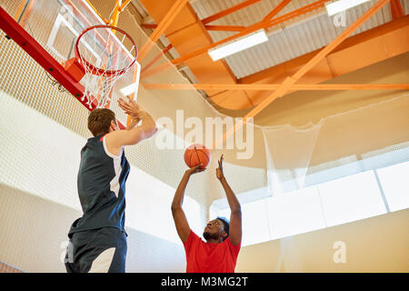 Sportliches Spieler wirft Ball im Korb Stockfoto