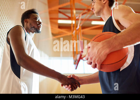 Ernsthafte Basketball Spieler aus verschiedenen Team Hände schütteln Stockfoto