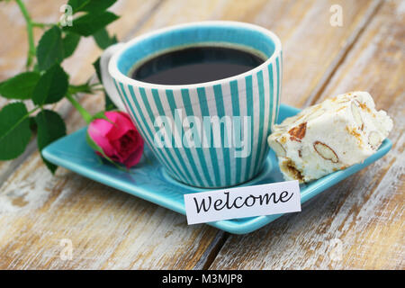 Karte Willkommen bei einer Tasse Kaffee, süße Nougat und pink Wild Rose auf Holzmöbeln im Landhausstil Oberfläche Stockfoto