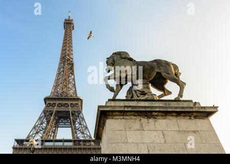 Low Angle Blick auf den Eiffelturm in Paris, von der Iena Brücke gegen den blauen Himmel gesehen, mit einem Equestrian Stein Statue im Vordergrund. Stockfoto