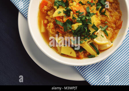 Rote Linsen Eintopf auf das runde weiße Platte. Ansicht von oben. Veganes Gericht mit Kartoffeln, Karotten und Kurkuma. Europäische Küche. Vegetarisches Mittagessen. Stockfoto