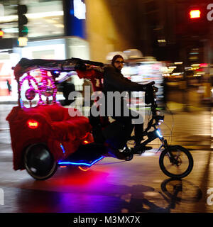 Rikscha Fahrer auf der Suche nach Flugpreise bei Nacht auf der Oxford Street, London, England, Großbritannien Stockfoto