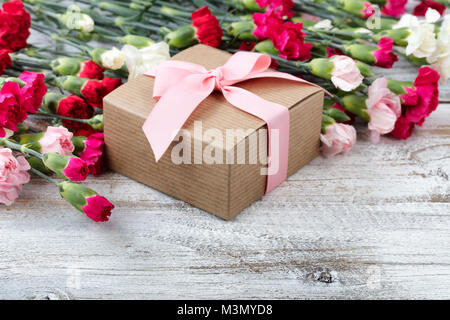 Geschenkbox mit bunten Nelken im Hintergrund auf weißen verwitterte Holzbretter Stockfoto