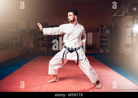 Kampfkunstmeister in weißen Kimono mit schwarzem Gürtel Karate, Karate Training im Fitnessraum Stockfoto