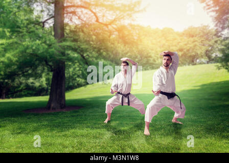 Martial Arts Karate Meister im weissen Kimono und Black Belts, Training im Sommer Park Stockfoto