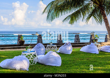 Hochzeit Setup in der Nähe des Ozeans bei Sonnenuntergang - weiße Bohne Beutel für Gäste und Rattan Tische Stockfoto