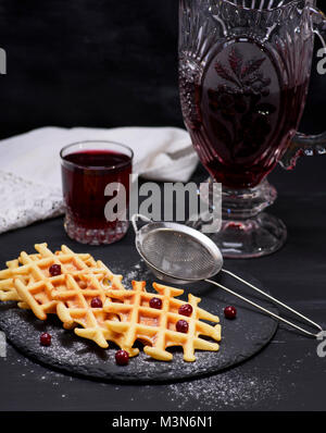 Gebackene Waffeln und Kompott in einem Glas auf schwarzem Hintergrund Stockfoto