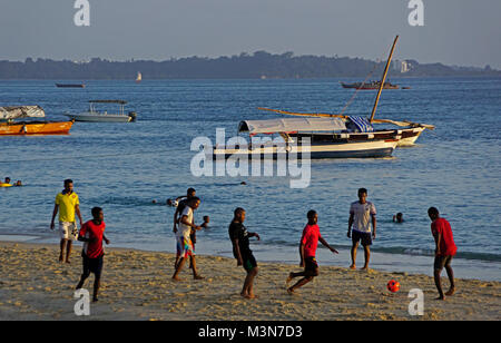 Junge Männer Fußball spielen am Strand von Stone Town Harbour in Sansibar. Stockfoto