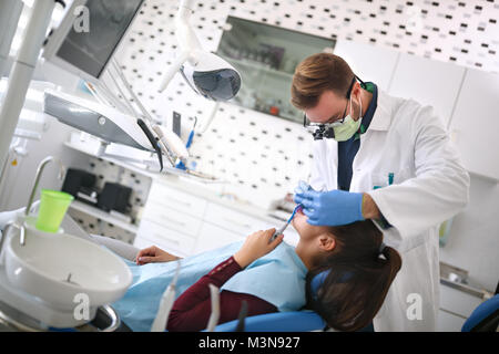 Männliche Zahnarzt untersucht die Zähne der Mädchen auf zahnmedizinische Klinik Stockfoto