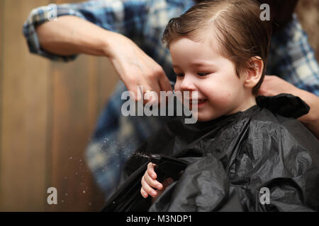 Ein kleiner Junge ist in hellen die Emotionen der Friseur auf getrimmt Stockfoto