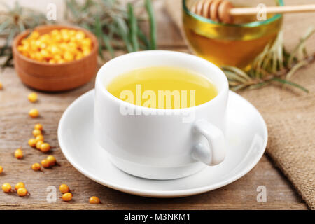 Sanddorn Tee in eine weiße Tasse auf den Tisch. In der Nähe von Laien Beeren Sanddorn und Honig Stockfoto