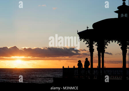 Ein paar genießen Sie die Aussicht auf den Sonnenuntergang beim Musikpavillon an der Strandpromenade Hoves entfernt als eines der schönsten Beispiele eines viktorianischen Musikpavillon in Großbritannien zu werden. Stockfoto