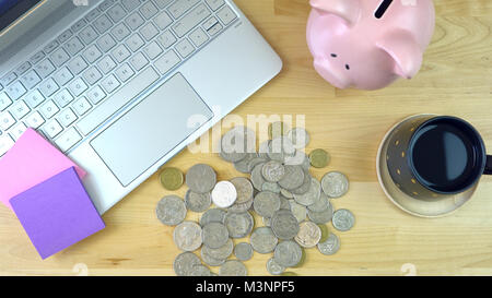 Moderne Büro Schreibtisch Overhead mit piggy Bank, Bargeld und Computer Laptop. Stockfoto