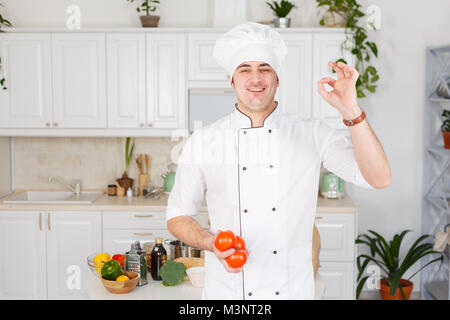 Koch mit Tomaten in der hand Geste auf Ok. Stockfoto