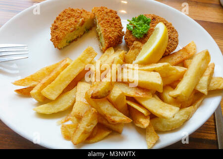 Ein Café das Mittagessen von geräuchertem Schellfisch Fischfrikadellen mit Pommes frites einer Scheibe Zitrone und Petersilie garnieren Fisch Kuchen aufgeschnitten Stockfoto