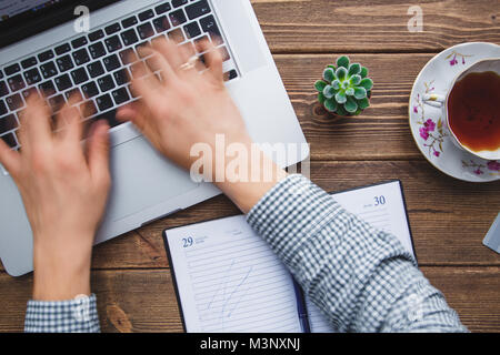 Mann bei der Arbeit am Laptop auf dem Schreibtisch platziert Stockfoto