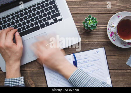 Mann bei der Arbeit am Laptop auf dem Schreibtisch platziert Stockfoto