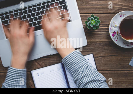 Mann bei der Arbeit am Laptop auf dem Schreibtisch platziert Stockfoto