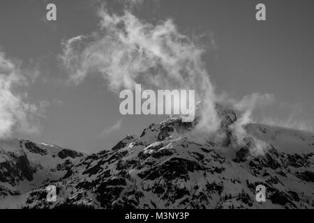 Schwarz-weiß Foto von schneebedeckten Berggipfel mit Wind Wolken Stockfoto