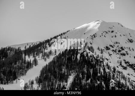 Schwarze und weiße geschossen von den letzten Strahlen der Sonne schlagen die schneebedeckten Gipfel eines Berges in den Alpen Stockfoto