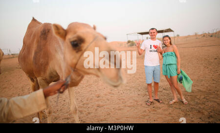 Mädchen und der Kerl mit dem Kamel. Wüste in Abu Dhabi, Vereinigte Arabische Emirate. Stockfoto