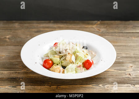 Hühnchen Caesar Salat mit Salatblättern in Weiß Schüssel auf hölzernen Tisch Stockfoto