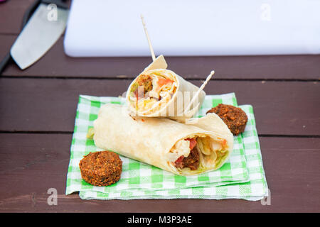 Der Straße Essen, vegetarische Gemüse wrap serviert auf dem Papier Serviette. Die grüne letuce, Tomaten, Zwiebeln und 2 Stück von kichererbsen Falafel. Stockfoto