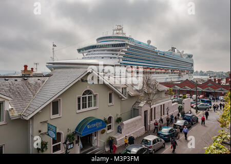 Das Kreuzfahrtschiff Emerald Princess ragt über dem Water's Edge Hotel, während es am Cobh Cruise Terminal, Cobh, Port of Cork, Irland, ankert. Stockfoto
