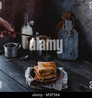 7/8 Schuß von Frau gießen Toast mit Honig Stockfoto