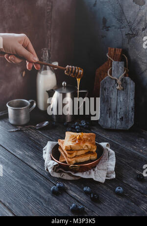 7/8 Schuß von Frau gießen Toast mit Honig Stockfoto