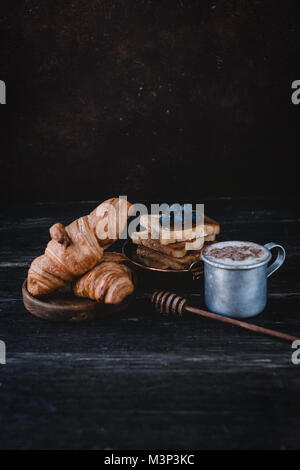 Nahaufnahme Blick auf Croissants, Toast mit Blaubeeren und Trinken auf hölzernen Tischplatte Stockfoto