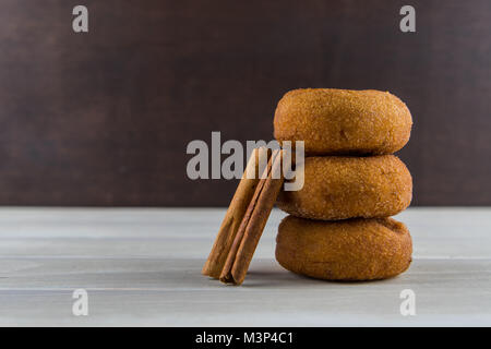 Zimtstangen lehnte sich auf Donuts auf der Tischplatte Stockfoto