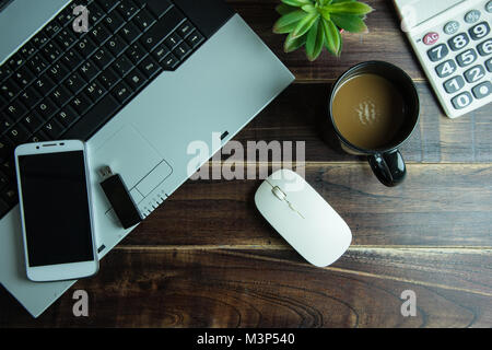 Blick von oben auf die Office Material mit smart phone Laptop wireless Maus und Kaffee Tasse auf Holztisch. Konzept Arbeitsplatz Stockfoto