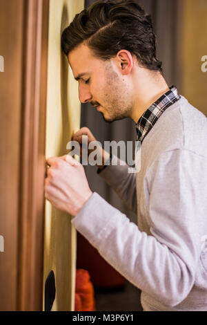 Seitenansicht des Jungen eleganten Mann lehnte sich an der Wand mit Kopf und Fäusten, nachdenklich. Stockfoto