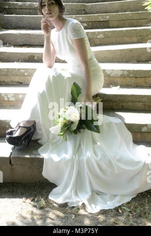 Eine schöne dunkelhaarige Braut tragen eine teure Hochzeit Kleid an einem sonnigen Tag - Hell Stockfoto