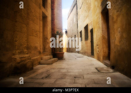 Einer typischen schmalen und historische Straße mit Kopfsteinpflaster Wände in Mdina, Malta. Stockfoto