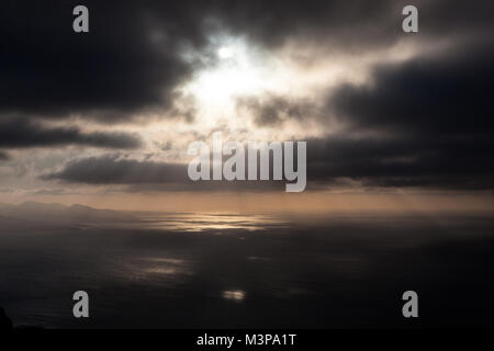 Haría, Batería del Río, Lanzarote, Las Palmas/Spanien: Blick auf einen atemberaubenden Sonnenuntergang am Meer von der Küste in der Nähe von Haría an einem bewölkten Tag Stockfoto